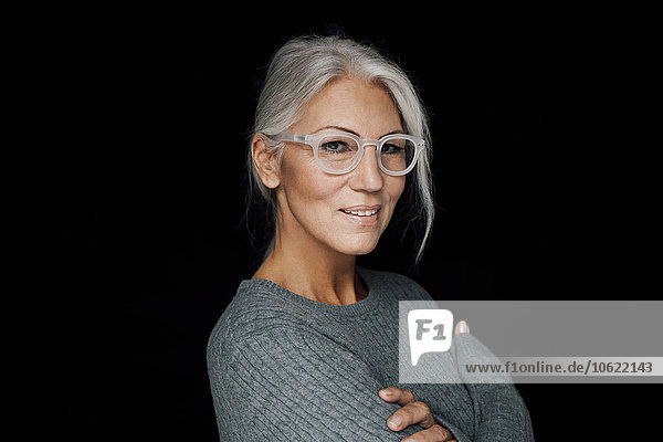 Portrait of smiling woman wearing glasses in front of black background