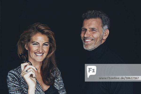 Portrait of happy couple in front of black background