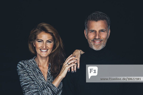 Porträt des lächelnden Paares vor schwarzem Hintergrund