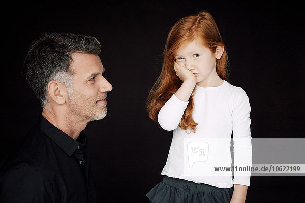 Father and little daughter in front of black background