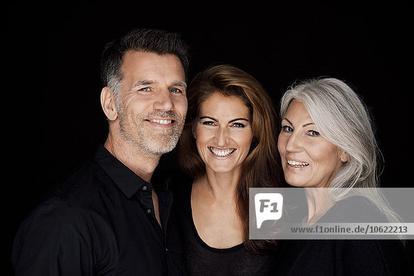 Portrait of three smiling people in front of black background
