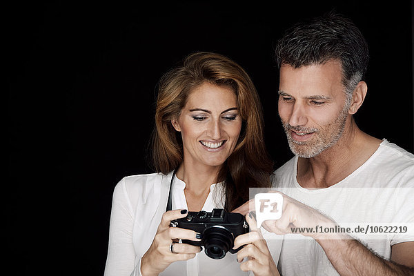 Porträt von Mann und Frau mit Blick auf die Kamera vor schwarzem Hintergrund