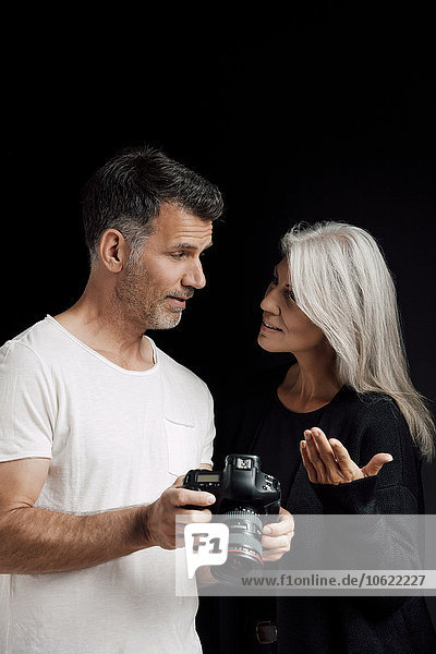 Mann und Frau mit Kamera vor schwarzem Hintergrund