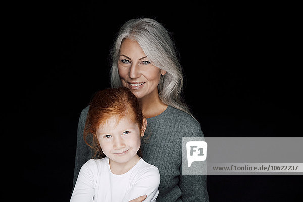 Porträt einer Frau mit ihrer kleinen Enkelin vor schwarzem Hintergrund