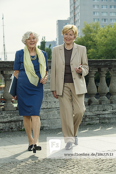 Deutschland  Berlin  Porträt zweier lächelnder Seniorinnen mit Laptop und Smartphone