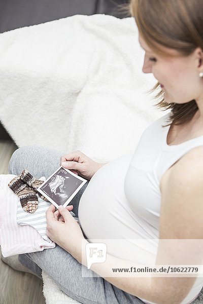 Schwangere junge Frau beim Betrachten des Ultraschallbildes