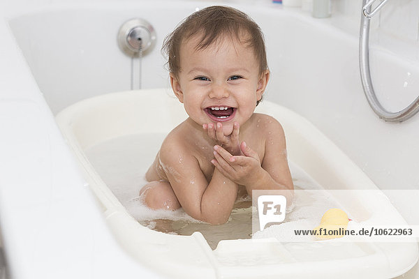 Porträt des lachenden Mädchens beim Baden in der Badewanne