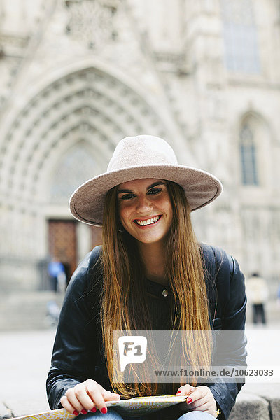 Spanien  Barcelona  Portrait einer lächelnden jungen Frau mit Karte