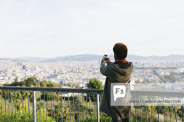 Spanien  Barcelona  Rückansicht eines jungen Mannes  der mit seinem Smartphone fotografiert.