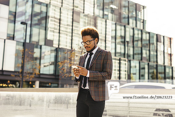 Young businessman outdoors looking at cell phone