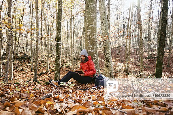 Spain  Catalunya  Girona  female hiker sitting in the woods reading book