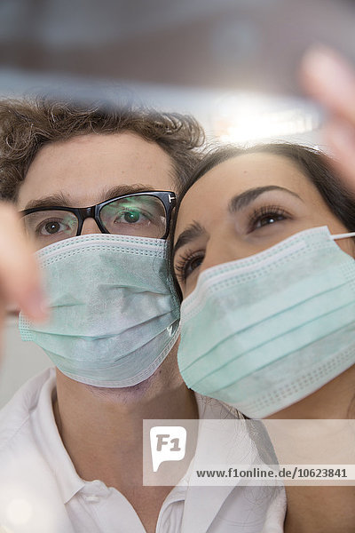 Zwei Ärzte mit Mundmasken beim Betrachten des Röntgenbildes