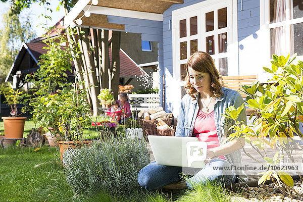 Junge Frau mit Laptop im Garten