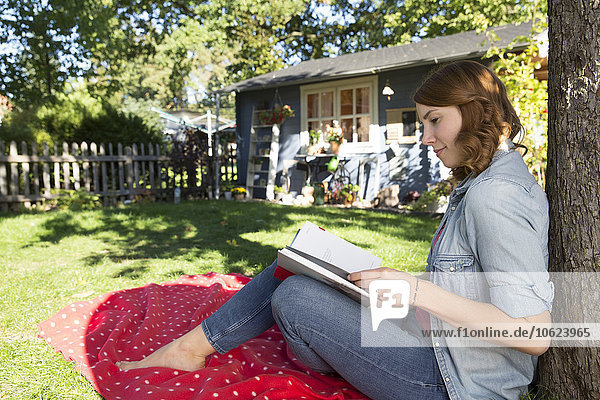 Junge Frau liest Buch im Garten