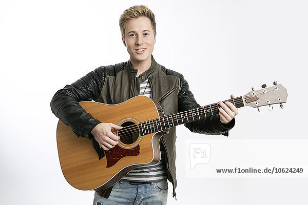 Lächelnder junger Mann beim Gitarrespielen