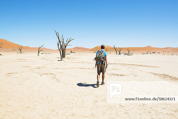 Namibia  Namib Desert  man with backpack walking through Deadvlei