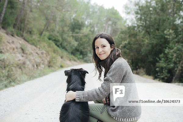 Porträt einer lächelnden Frau mit ihrem Hund in der Natur