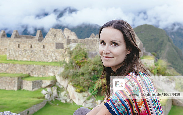 Peru  smiling woman in Machu Picchu citadel with Huayna Picchu mountain in the background