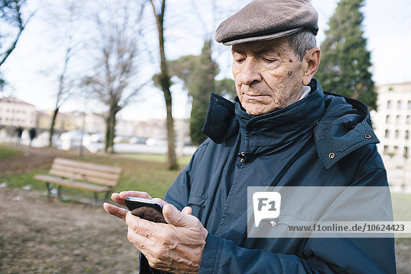 Portrait of senior man with smartphone in a park