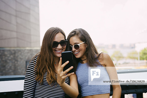 USA  New York City  two smiling friends looking at cell phone