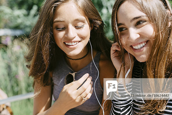 Two happy friends sharing earphones