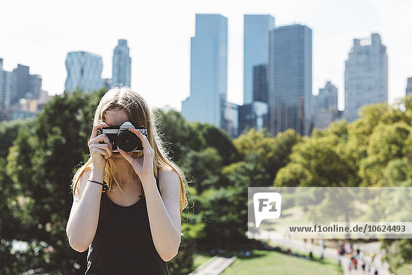 USA  New York City  junge Frau beim Fotografieren im Central Park