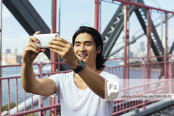 USA,  New York City,  Mann auf der Williamsburg Bridge in Brooklyn mit einem Selfie