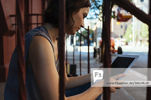 USA  New York City  Frau auf der Treppe sitzend mit digitalem Tablett