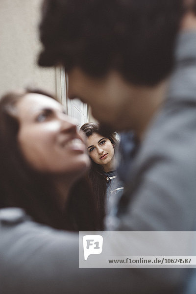 Young couple kissing with another woman looking at them