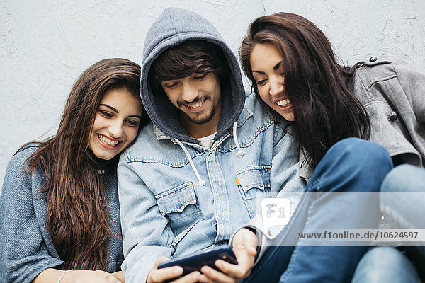 Drei Freunde im Freien beim Blick auf das Handy