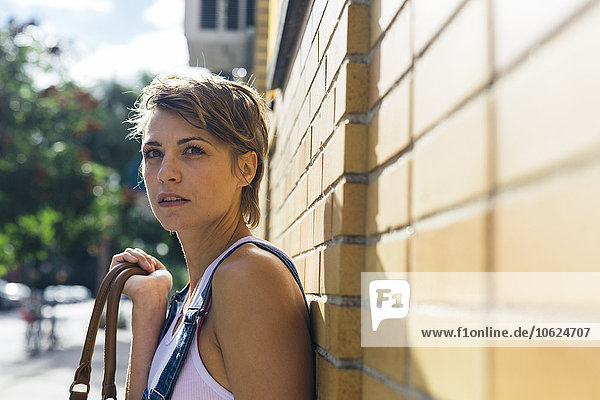 Portrait of waiting blond woman leaning against a wall