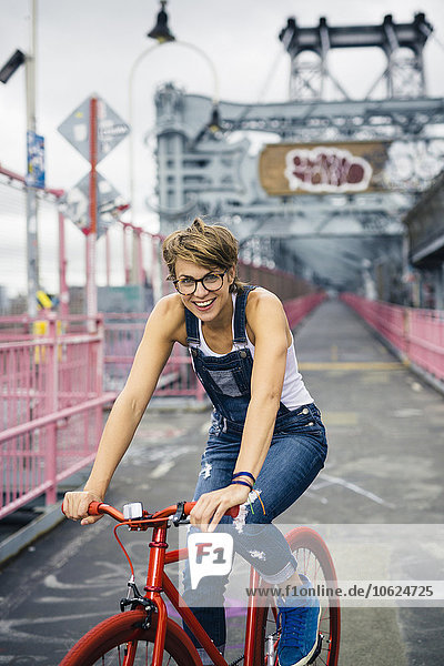 USA  New York City  Williamsburg  Porträt einer blonden Frau mit rotem Rennrad auf der Williamsburg Bridge