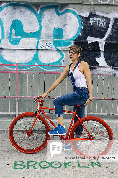 USA  New York City  Williamsburg  blonde Frau mit rotem Rennrad auf der Williamsburg Bridge