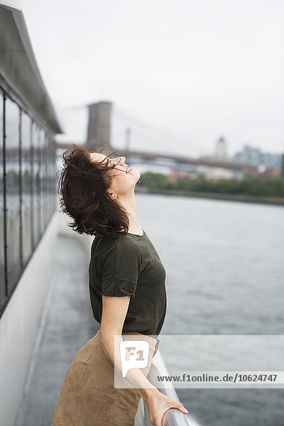 USA,  New York City,  junge Frau an einem windigen Tag auf einem Ausflugsboot stehend