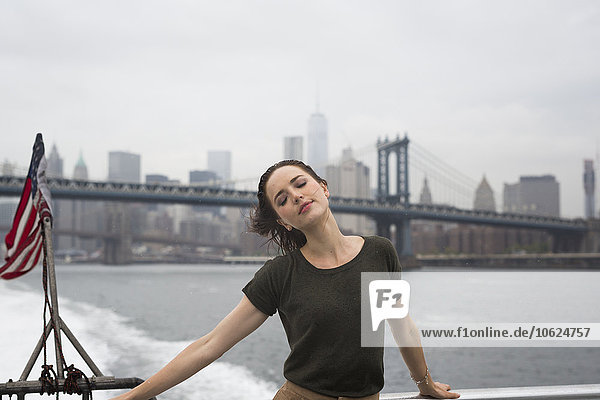 USA  New York City  junge Frau an einem windigen Tag auf einem Ausflugsboot stehend