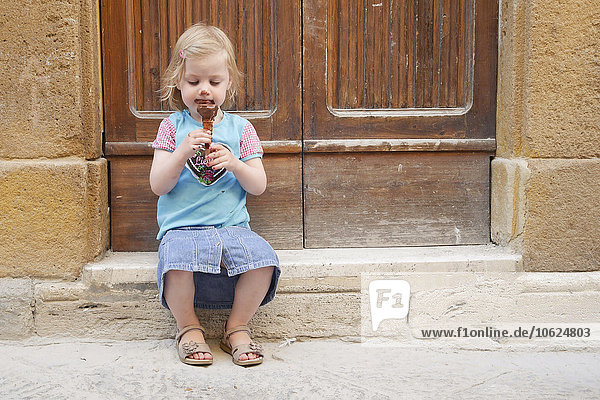 Girl with chocolate ice cream cone sitting on stoop