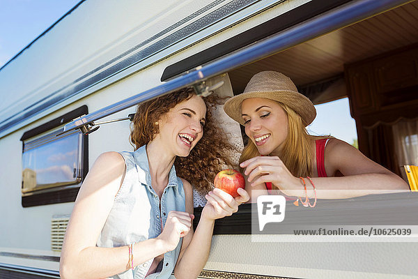 Zwei Freundinnen im Urlaub mit einem Wohnwagen