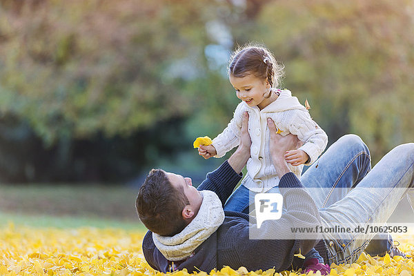 Happy father with daughter in autumn leaves