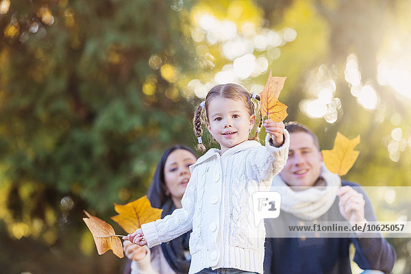 Smiling girl with family holding autumn leaf