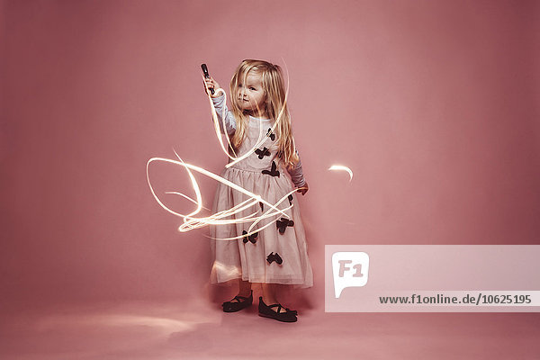 Kleines Mädchen Lichtgemälde mit einer Taschenlampe vor rosa Hintergrund