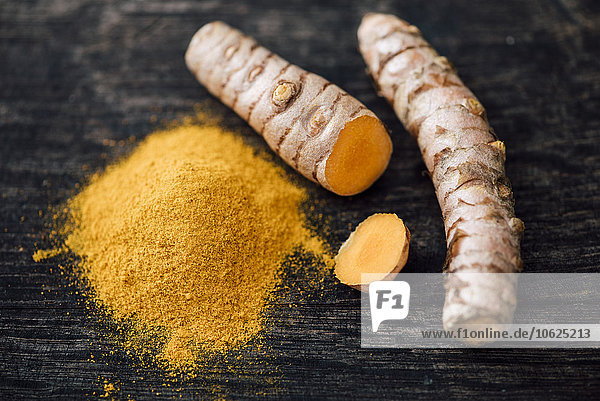Frisches Curcuma und Pulver auf Holz