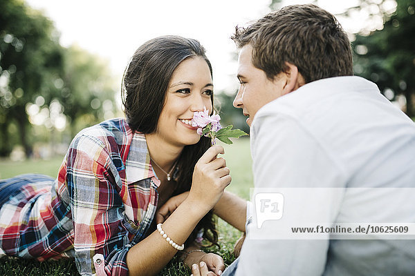 Young couple in love lying face to face on a meadow in a park