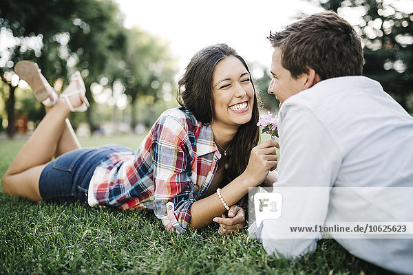 Young couple in love lying on a meadow in a park