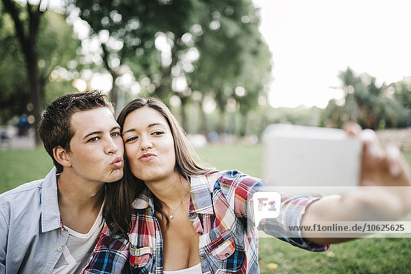 Porträt eines verliebten jungen Paares  das einen Selfie mit Smartphone im Park nimmt