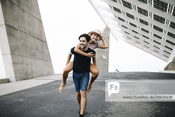 Spain  Barcelona  young man giving his girlfriend a piggyback ride