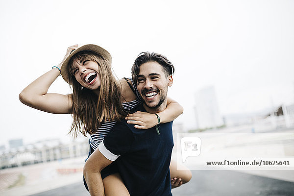 Spain  Barcelona  young man giving his girlfriend a piggyback ride