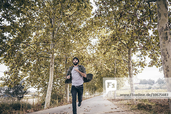 Spain,  Tarragona,  young man running on autumnal country road