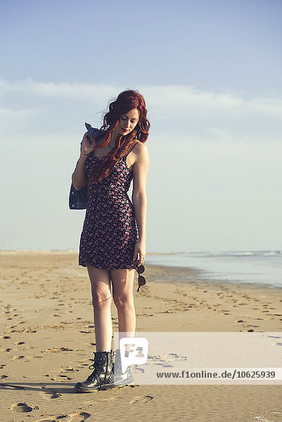 Spain  El Puerto de Santa Maria  portrait of redheaded young woman standing on the beach