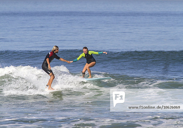 Mann hilft Frau auf dem Surfbrett