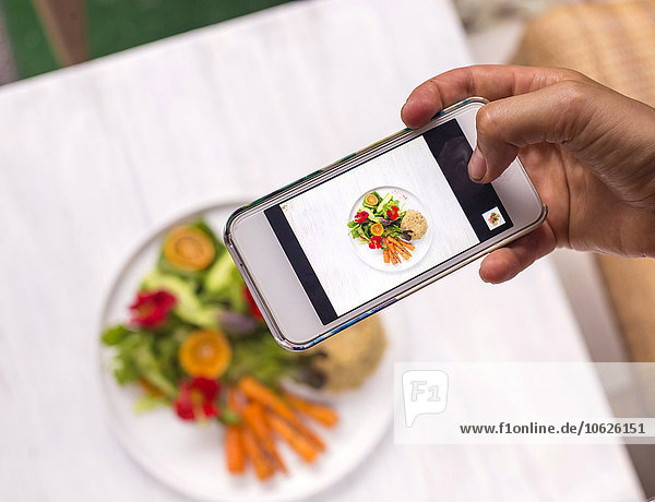 Woman taking a photo of dish with vegetables and quinoa  close-up